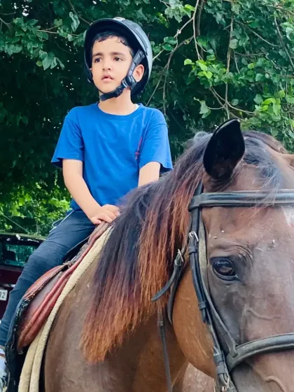 A young boy sits tall on his horse, focused and ready for his lesson. We teach posture and balance from the very first ride.