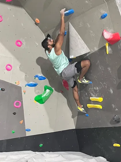 This climber uses a combination of strength and balance to move up a technical section of the wall, showing intense focus and control.