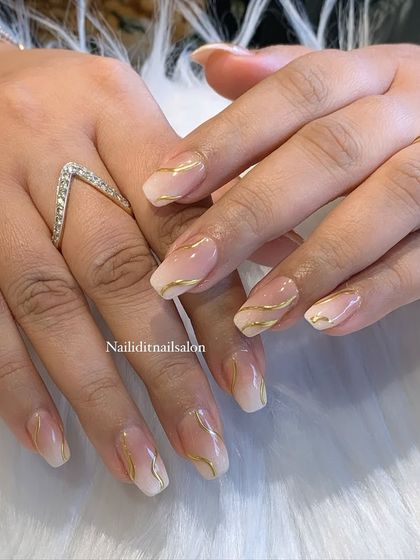 A subtle and stylish design on shorter, square-shaped nails. This look features a soft ombre base with delicate gold chrome swirls for a touch of everyday luxury.