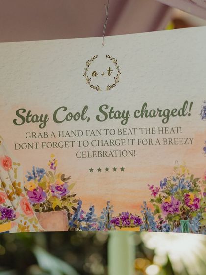 A close-up of the sign for the hand fan station, featuring beautiful watercolor floral artwork that matches the event's stationery.