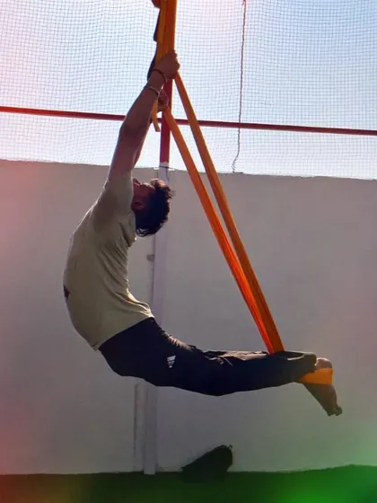 A student enjoying a deep backbend in the orange hammock. The open air studio adds to the experience.