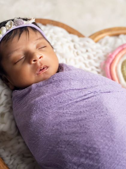 A close-up on this sleeping beauty, showing the delicate details of her shell and pearl headband in our lavender and rainbow-themed newborn setup.