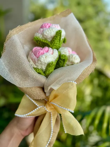 A delicate bouquet of pink and white tulip-style buds, wrapped in jute with a pearl-studded bow. It's a sweet and elegant arrangement.