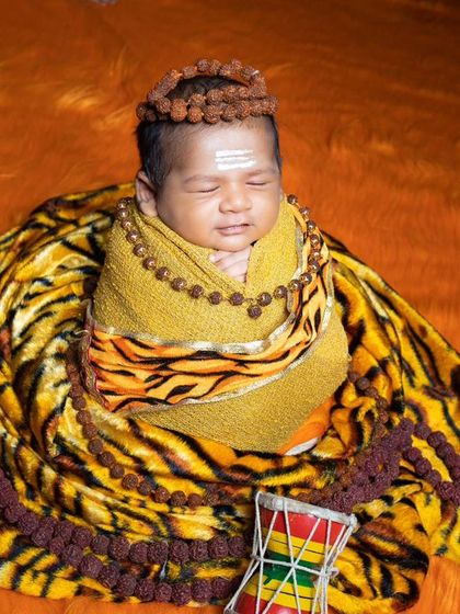 This newborn is smiling in his sleep, dreaming divine dreams as little Lord Shiva.