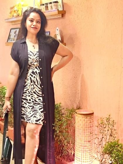 This outfit shows how to style a bold animal print dress by layering it with a long black shrug. It's a great example of balancing statement pieces for a polished yet edgy look.