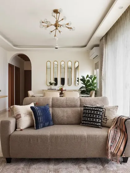 An overview of the open-plan living room, designed for a young couple who loves to host. The space incorporates TV, crockery, and pooja units with a cohesive design language of curves and grooves.