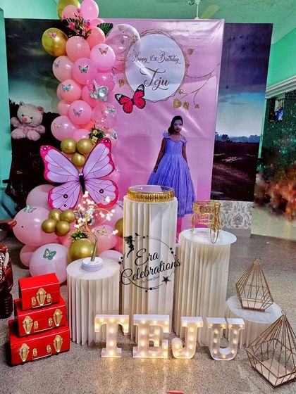 Another angle of the personalized butterfly-themed home birthday decor. This image showcases the full setup with plinths, a custom banner, and marquee letters for the name 'TEJU'.