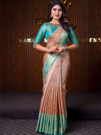 This model is wearing a unique beige and teal saree. The drape is styled to highlight the unusual color combination and the intricate blouse neckline.