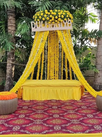 A classic 'Dulhaniya' Haldi setup for the bride. This design features a comfortable seating area framed by beautiful marigold curtains and traditional matkas.