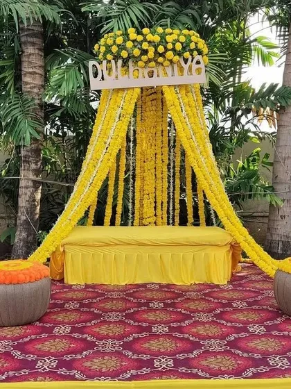 A classic 'Dulhaniya' Haldi setup for the bride. This design features a comfortable seating area framed by beautiful marigold curtains and traditional matkas.