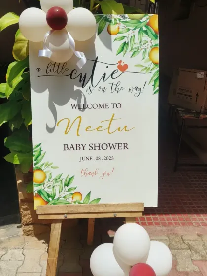 A custom welcome sign for a baby shower with a "little cutie" orange theme, placed on an easel to greet guests at the entrance.