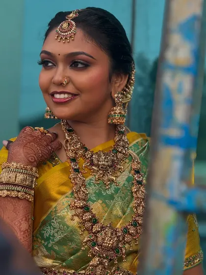 A candid outdoor shot of Prithivi. The natural light beautifully captures the details of her makeup and the richness of her antique gold jewellery.