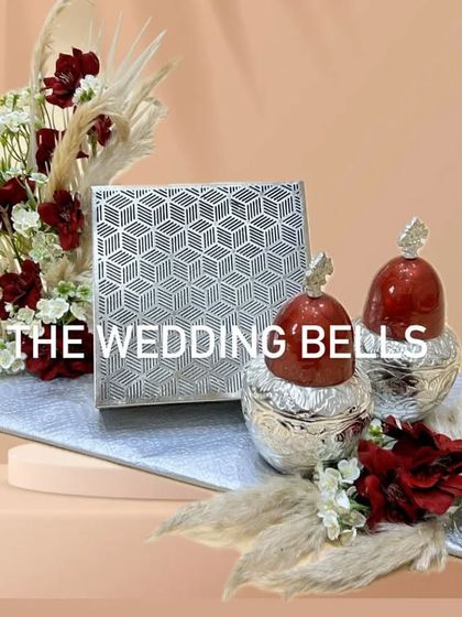 A sophisticated Diwali hamper in a silver and maroon theme. It includes two dry fruit jars and a box of besan barfi on a silver base.