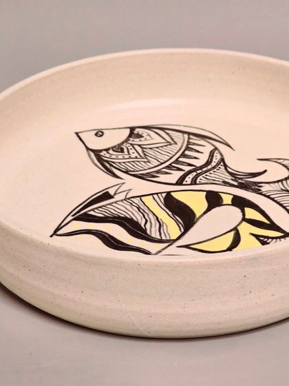 This sold plate features a playful design of two fish with pops of yellow. It's a perfect example of how my hand-painted ceramics can transform a wall into a canvas of art.