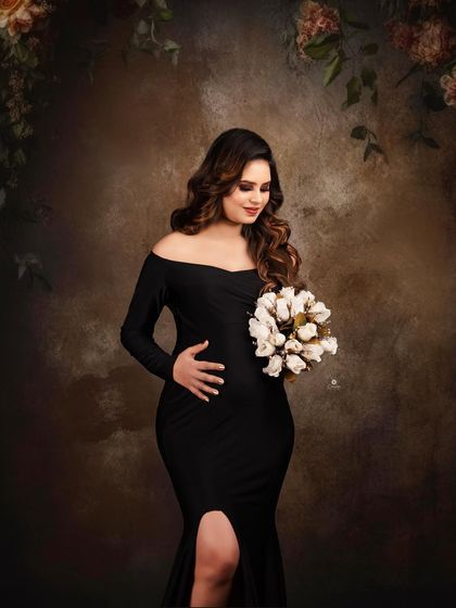 A beautiful portrait in a black off-shoulder gown, with the client holding a bouquet of white flowers. The contrast between the dark dress and the light flowers creates a striking visual.