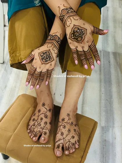 A complete look for an engagement ceremony, with matching mehendi on the hands and feet. The hands feature custom initial mandalas, while the feet have a delicate floral vine pattern.