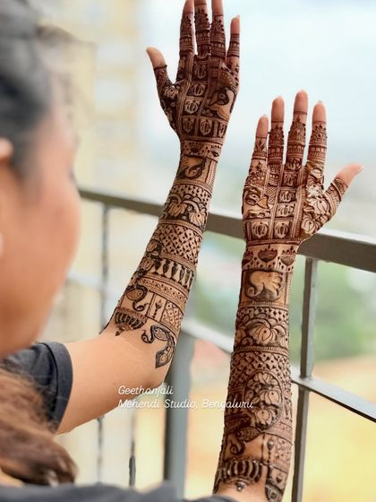 A beautiful shot of the engagement mehendi against a scenic background, showing the full arm design.