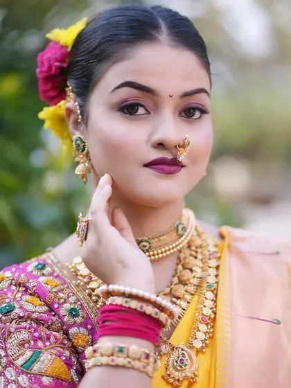 A close up on the details of a traditional Maharashtrian look. The focus is on the classic winged eyeliner, a bold lip color, and the iconic Maharashtrian nath, which completes the bridal attire.