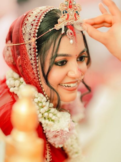 A close-up during the sindoor ceremony, her smile and glowing skin are the focus.