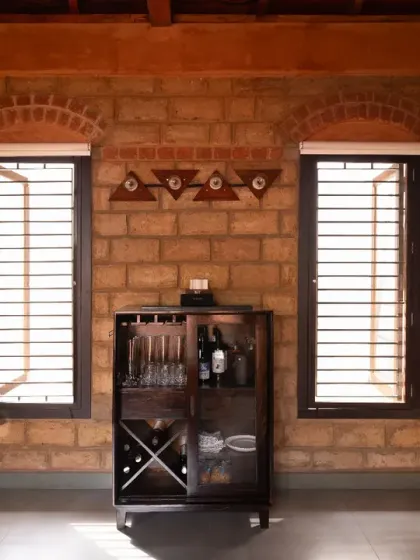 The bar lounge at project Vinaya features exposed, stabilized earthen block masonry. The subtle texture of the mud bricks, combined with the small brick arches above the windows, adds a rustic and warm character to the space.