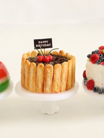 A collection of three miniature cakes: watermelon jelly, chocolate birthday, and a berry-topped cake.