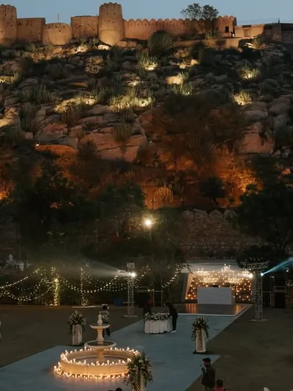 The magical setup for a reception at Mundota Palace, with the historic fort illuminated in the background. This image showcases the breathtaking ambiance of a nighttime celebration in Jaipur.