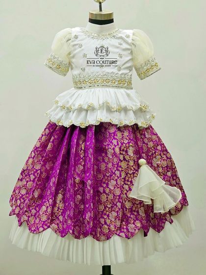 A lovely white and purple Banarasi lehenga with a tiered peplum blouse and a layered, scalloped skirt.