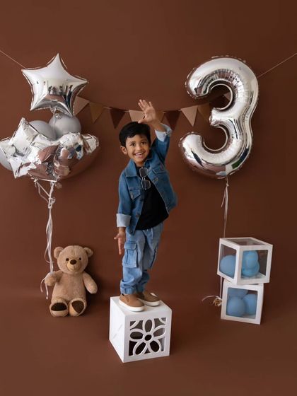 Waving hello to year three. A happy toddler stands on a block during his modern, stylish birthday photoshoot.