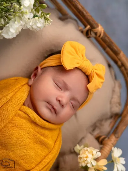 A sweet close-up of the newborn's face, with a cute yellow bow headband.