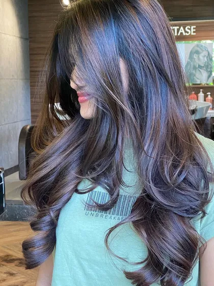 This image captures the movement and dimension of a dark brunette balayage. The subtle, cooler-toned highlights are woven through to create texture and depth.