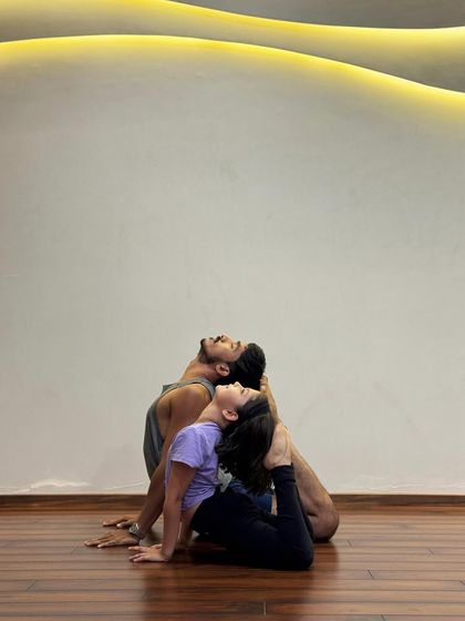 A beautiful partner variation of Ustrasana (Camel Pose), showing trust and shared energy.