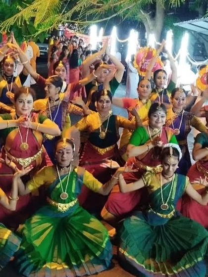A wide shot of the dancers assembled for the street performance, showing the scale and festive atmosphere of the Ganesha procession.
