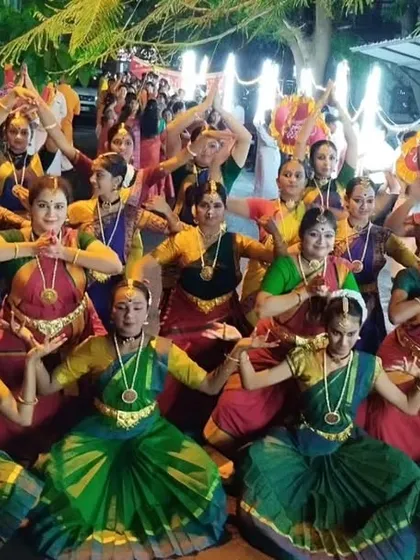 A wide shot of the dancers assembled for the street performance, showing the scale and festive atmosphere of the Ganesha procession.