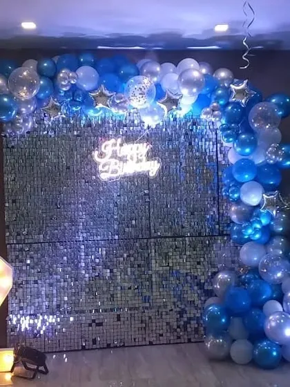 The full view of the silver sequin wall backdrop under blue lighting, creating a cool, celebratory effect.