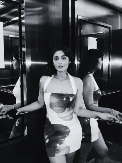 A moody, reflective shot of Dhvani Bhanushali in an elevator. This black and white photo captures the artistic vibe of her floral print dress from Runaway The Label.