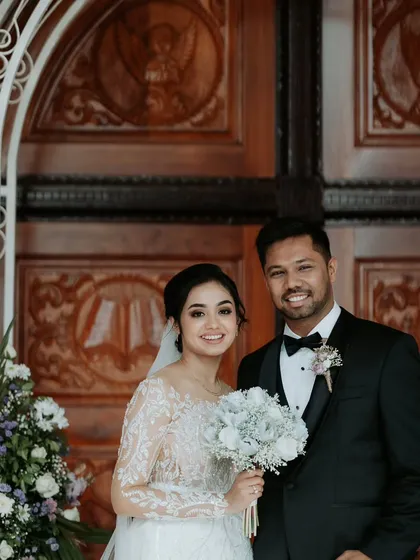 A sweet moment between the newly married couple. The simple floral decor at the church entrance provides a lovely, natural frame for this happy portrait.