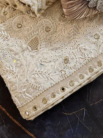 A detail shot of the folded saree, focusing on the border and the texture of the embroidery.