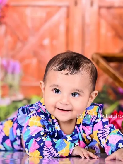 A smiling baby crawling in a colorful floral setup.