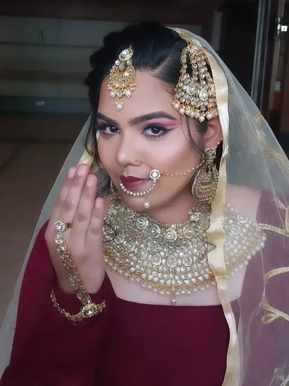 A traditional Muslim bridal look with a focus on heavy jewelry like the passa and nath. The eye makeup is bold with a winged liner to make a statement.
