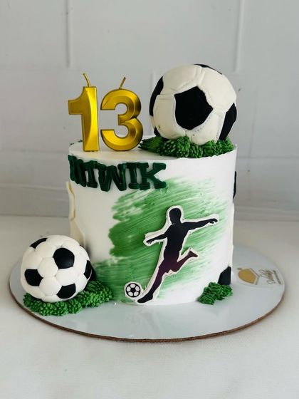 A cool football-themed cake with a green brushstroke effect and edible soccer balls.
