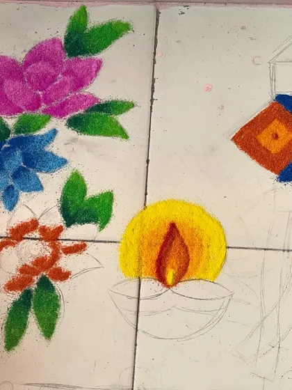 The beginning stages of a 'Shubh Deepavali' rangoli. The outlines are drawn, and the first layers of color are being filled in for the flowers and diya.