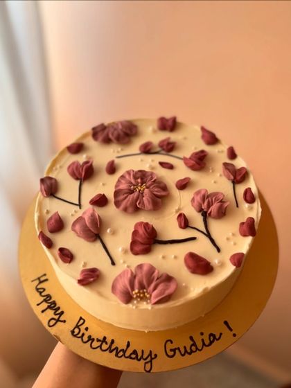A close-up of the vanilla sponge cake with homemade raspberry jam and white chocolate ganache, decorated with beautiful purple piped flowers.
