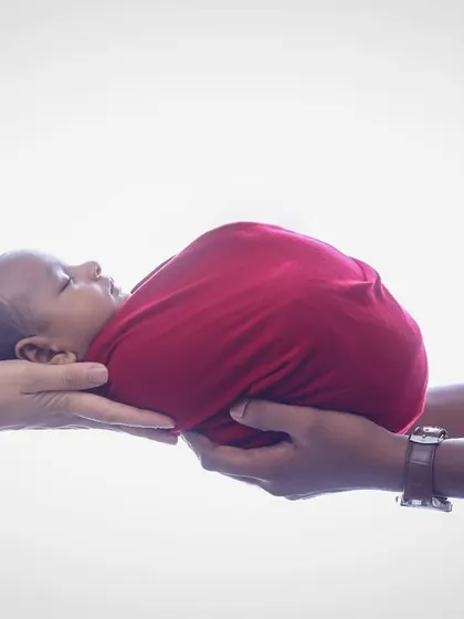 A simple yet powerful shot of a newborn baby being held securely in their parents' hands. This pose highlights how small and precious they are in these fleeting early days.