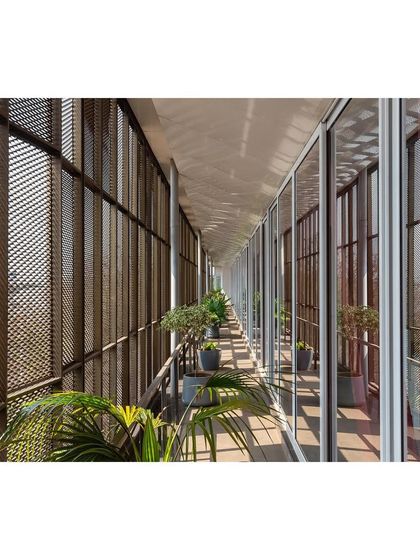 A linear verandah wrapped in an expanded aluminum mesh envelops the 'Hoverspace' office. This feature acts as a climatic buffer, a breakout space, and a semi-transparent screen that filters sunlight and offers views of the city.