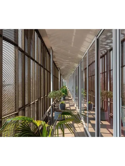 The linear verandah of "Hoverspace" is wrapped in an expanded aluminum mesh skin. This feature acts as a climatic buffer, shading the interior offices while allowing for views and natural ventilation.