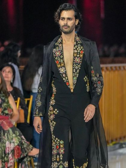 A runway shot of a male model in a stunning embroidered ensemble. My grooming work ensures the focus remains on the intricate details of the outfit while the model looks polished and confident.