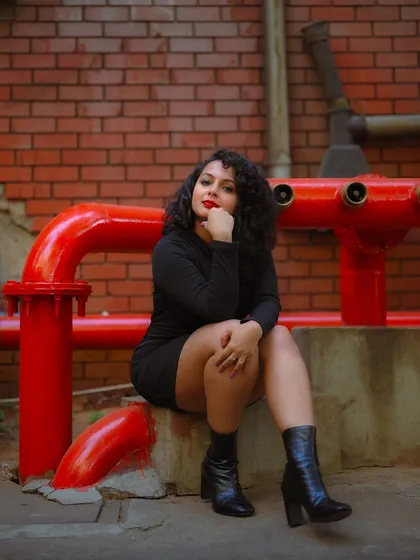 A duplicate of image 368, this seated portrait in an industrial setting uses the contrast of the model's dress and the red pipes to create a striking composition.