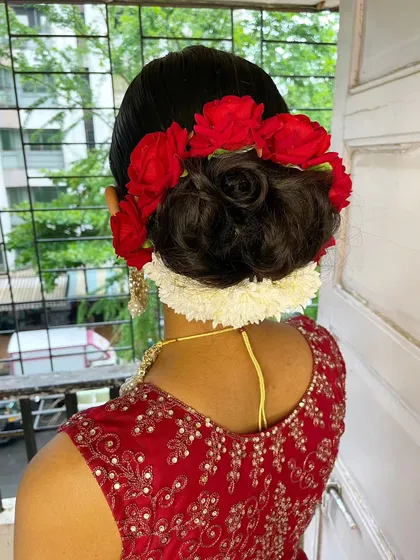A closer look at a personalized floral bun. I love incorporating fresh flowers into my hairstyles. Here, I've combined red roses with a string of gajra to create a bold and traditional hair accessory for a classic bridal updo. This is a perfect example of a custom wedding hairstyle.