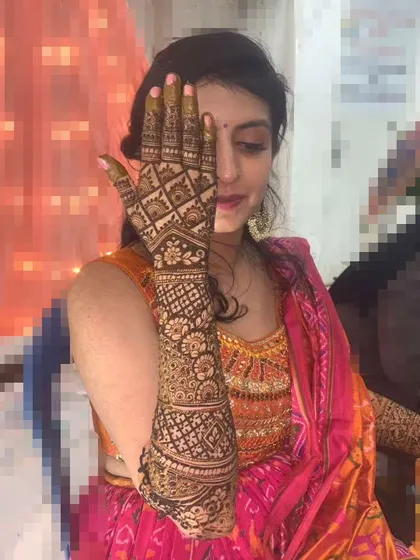This bride is showcasing her intricate, geometric-patterned bridal mehendi that extends all the way up her arm.