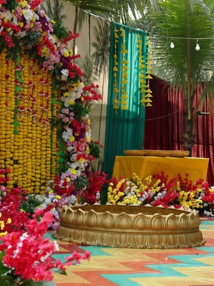 A traditional Haldi setup rich with marigolds and other colorful flowers. The floral arch and the brass urli for the ceremony are classic elements that we love to incorporate for an authentic and vibrant feel.